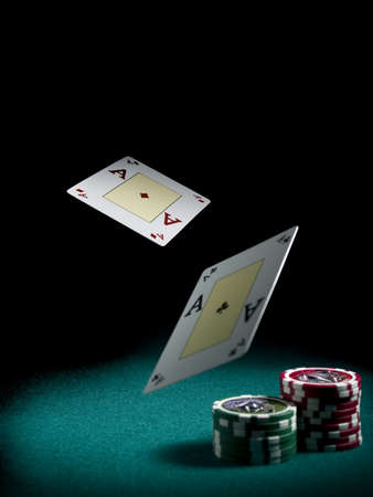 Two aces flying over a green felt with three piles of differents colors chips.