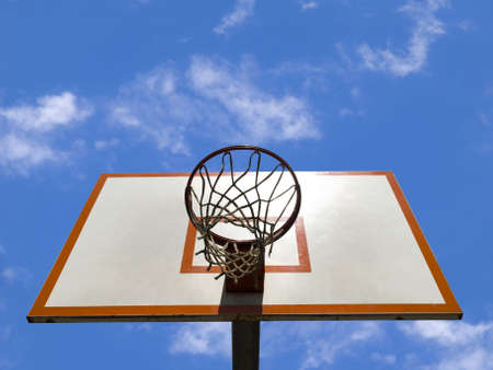 A basketball ring over a blue sky with clouds.の写真素材