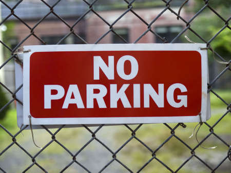 A No Parking sign hunging on a fence.の写真素材