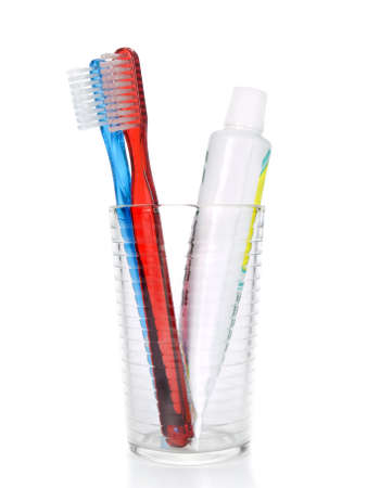 Two toothbrushes and a tube of toothpaste in a glass over white background.の写真素材