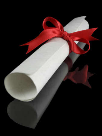 Diploma with a red silk ribbon, isolated on black background.の写真素材