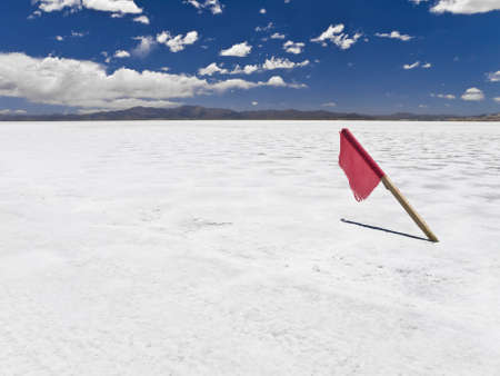 A red flag stuck in a huge salt field.の写真素材