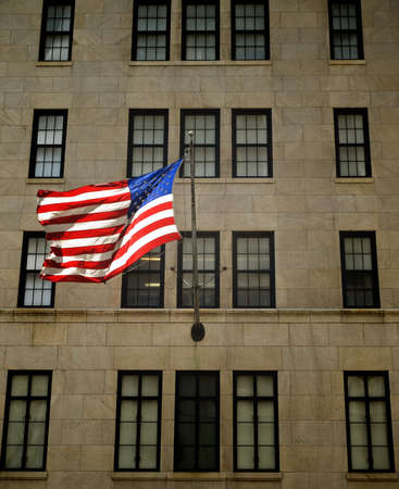 An American flag waving on the facade of a building.