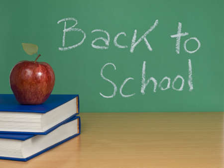 Back to school written on a chalkboard with an apple over books.