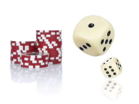 Pair of dice rolling in front of stacked red poker chips.