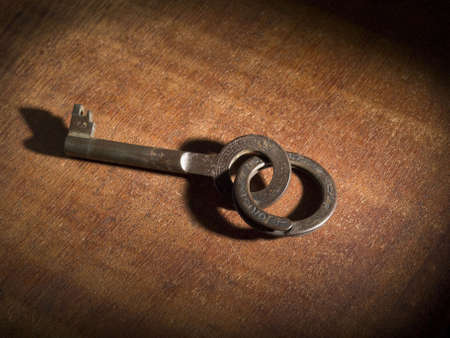 An old key on a keyring over a wooden table.の写真素材