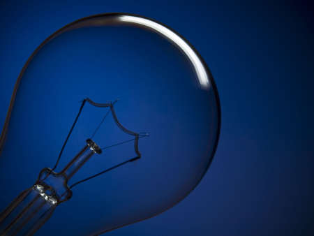 Close up on a transparent light bulb over a blue background.の写真素材