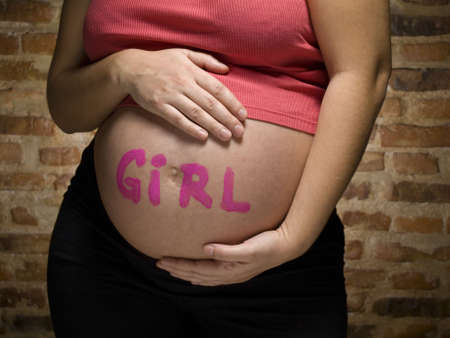 Pregnant woman with the word GIRL written in her belly.の写真素材