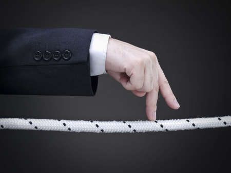 Close up of a businessman's fingers walking on the tightrope. Conceptual image. の写真素材