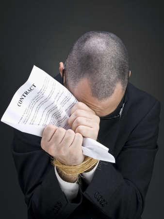 A man on a suit holds a contract on his tied hands.の写真素材