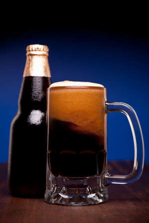 A glass and a bottle of beer on a wooden table.