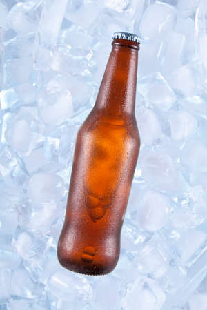 A brown bottle of beer on ice.の写真素材