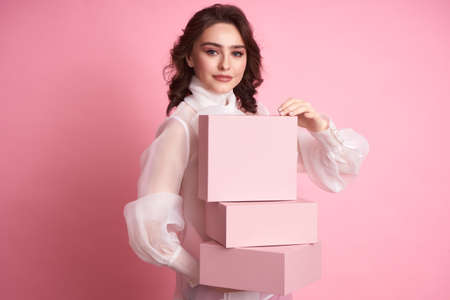 Young girl holding a pink box on a pink background