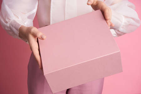 Close-up of a girl holding a pink box on a pink backgroundの写真素材