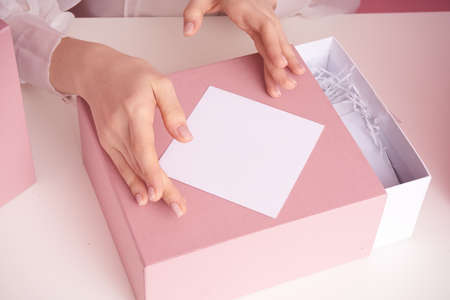 Female hands on a white table hold a box