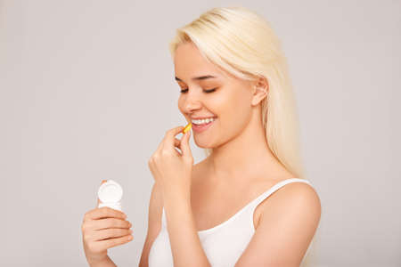 Beautiful girl taking medicine, vitamins, pills. Gray backgroundの写真素材