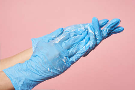 Hygiene. Female hands with gloves betray disinfect on a pink background. Hand washing to save a life. High quality photoの写真素材