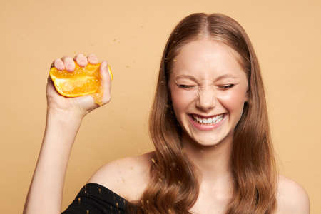 Beauty. Smiling woman with radiant face skin and orange portrait. Beautiful smiling european girl model with natural makeup, healthy smile and glowing moisturized face skin.の写真素材