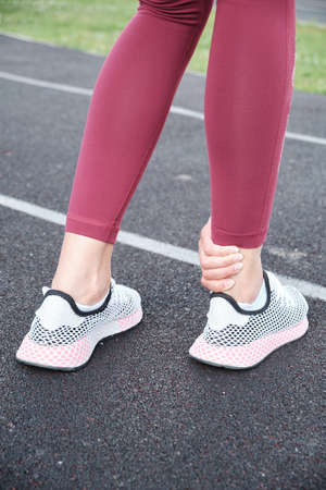 Girl in the stadium. Legs of the girl close-up foot injury. Woman suffering from leg pain after...
