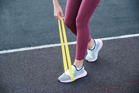 Close-up of female legs. The athlete stretches the resistance band against the background of the...
