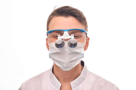 Doctor on a white isolated background. A doctor wearing a medical mask and wearing a device on his...