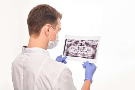 A medical worker with his back to the camera on a white isolated background looks at the pictureの写真素材