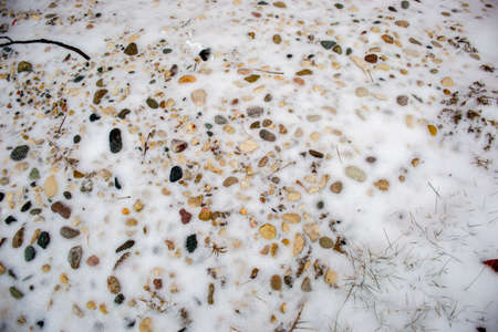 Pebbles in the snow with a littlebit of grass aroundの写真素材