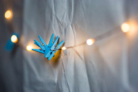 Tiny blue clips on string of lights against textured white background in macroの写真素材