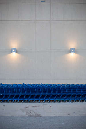 Line of blue shopping carts against wall with lightsの写真素材