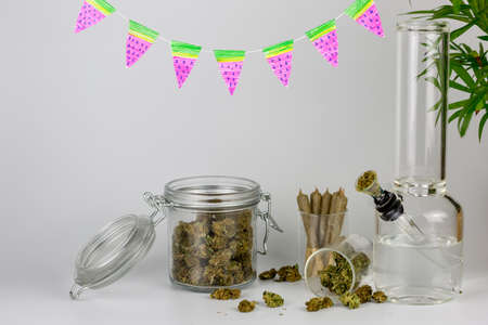 Assorted weed in glass jars with packed bong, cone joints, tropical plant and watermelon pennantsの写真素材