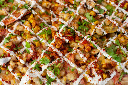 Close up of tortilla chips loaded with chicken, corn salsa, sour cream and fresh cilantro
