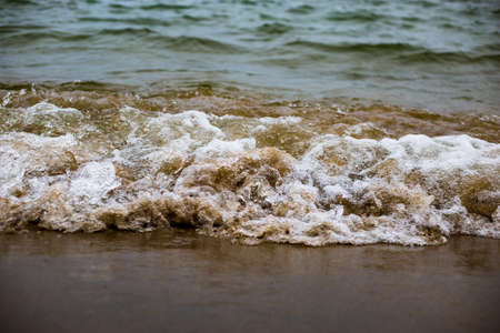 The cold waters of Michigan tumbling around with sand in springの写真素材