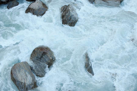 Stormy flow of white water in a mountain river among large bouldersの写真素材