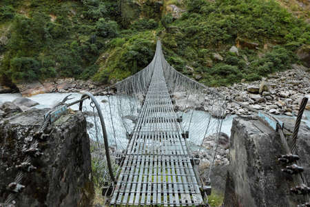 Suspension bridge over the rough mountain river in Nepalの写真素材