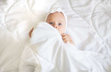 Cute baby in a blanket, smiles and laughs.の写真素材