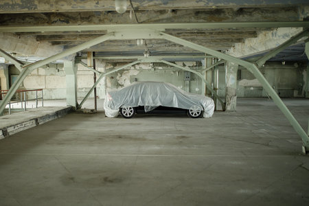 Car covered in a black cloth lying on the ground in a garageの写真素材