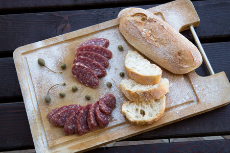 slices of bread with salami and spices on a wooden boardの写真素材