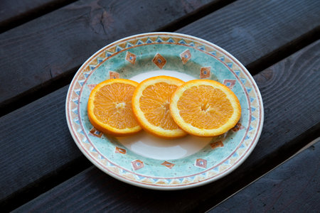 Slices of fresh orange on a plate on a wooden tableの写真素材