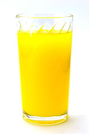 bright orange orange juice into a faceted transparent glass on a white light backgroundの写真素材