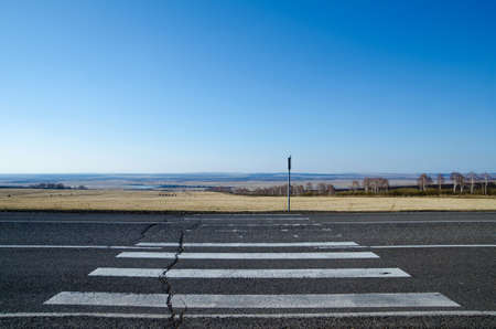 Cracked pedestrian crossing with a picturesque spring landscape as a background.の写真素材