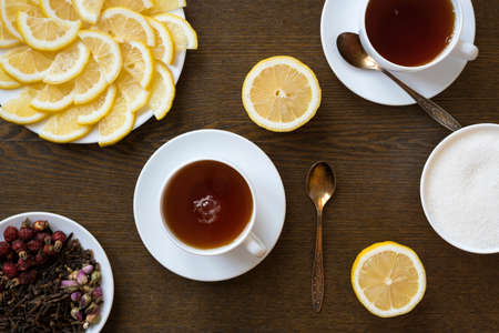 Two cups of tea with lemon on a wooden board.の写真素材