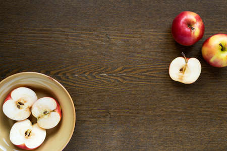 Apples in a clay dish on wooden board with copy space.