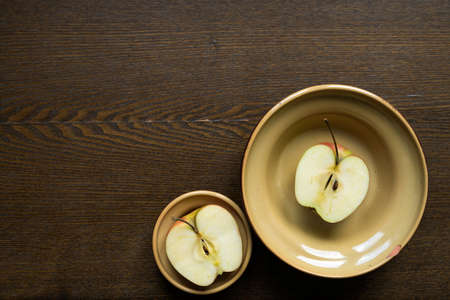Apple halves in clay dishes on wooden board with a copy space.の写真素材