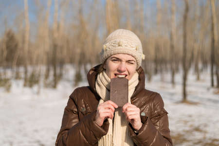 Woman eating a chocolate outdoors in a winter forest.の写真素材