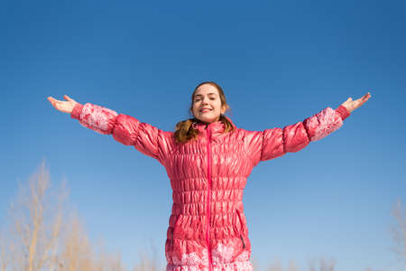 Woman in pink greeting the sun with her wide open arms.の写真素材