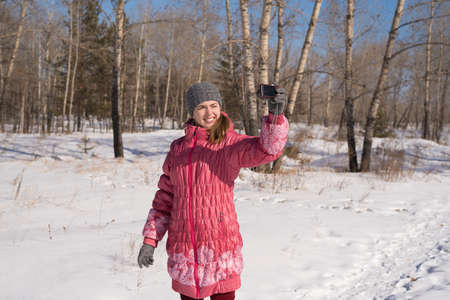 Woman in pink taking selfie on a winter sunny day.の写真素材