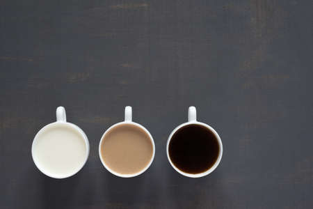 Three cups with coffee and milk on a painted board