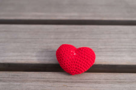 Crocheted heart on a wooden board with natural lightの写真素材
