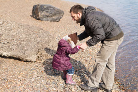 Father and daughter playing on a riverbank in spring timeの写真素材
