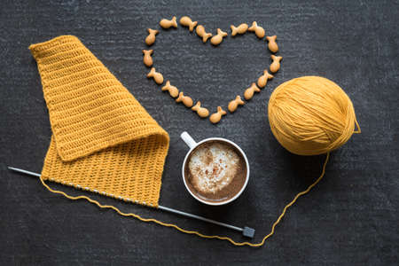 Knitting, cup of coffee and heart made of crackers on grunge background.の写真素材